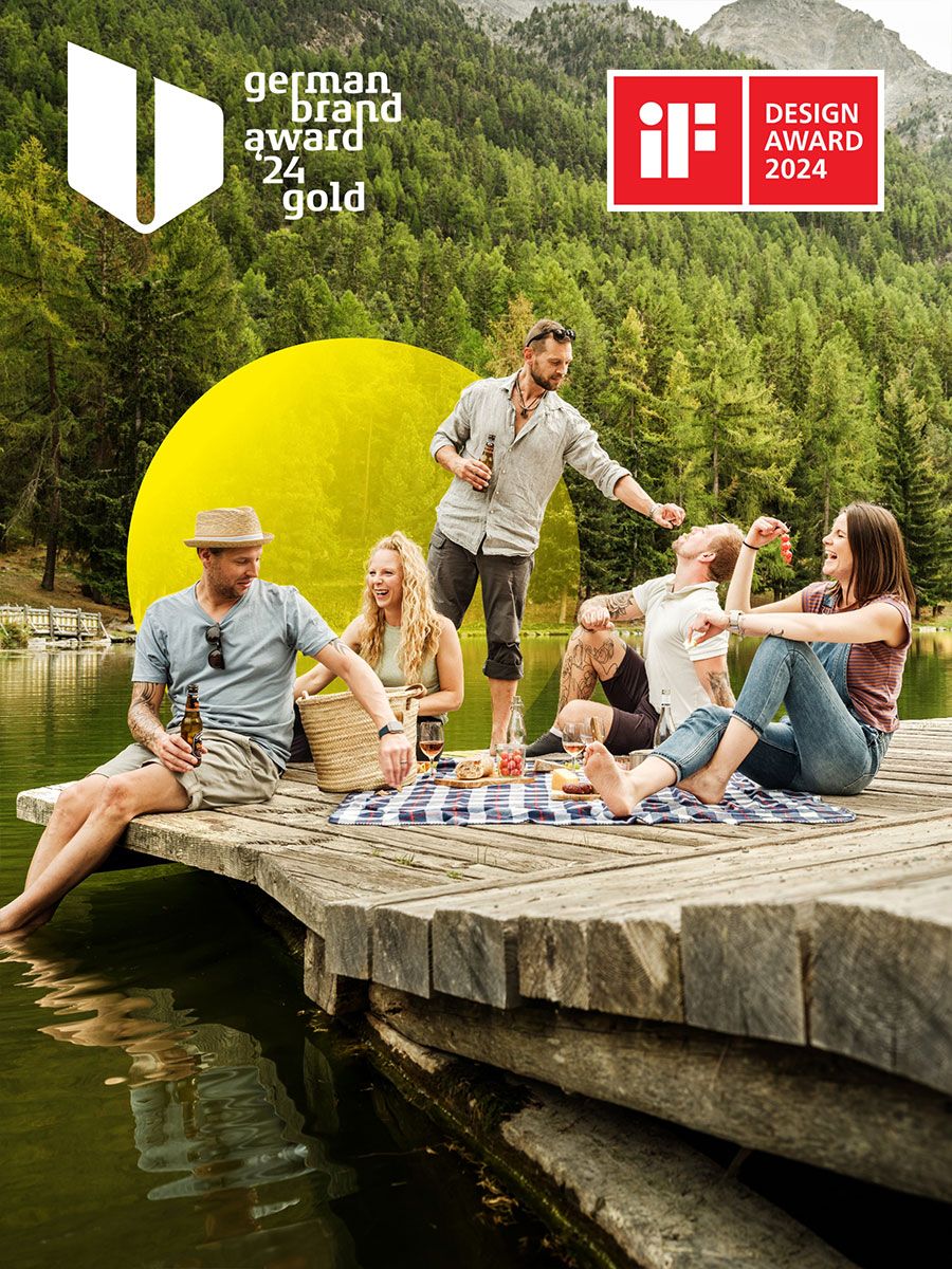 Freunde beim Picknick auf einem Steg beim Bergsee in Grächen